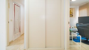 Una habitación con puerta corredera, una cama con cubierta azul, una silla y un televisor.