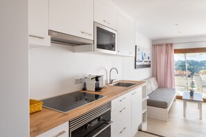 Cuina moderna amb microones, fogó i forn integrats. Hi ha un taulell de fusta, un rentapeus i una finestra amb vistes a l'exterior.