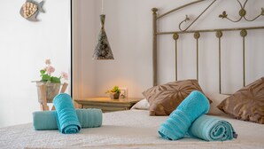 Ein ordentlich gemachtes Bett mit aufgerollten Handtüchern, einer Zimmerpflanze und einer Wanddekoration mit Fischmotiv.
