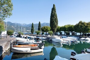 A marina with boats docked, a clear sky, and mountains in the background.