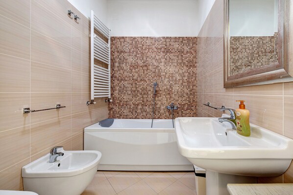 A bathroom with a bathtub, two sinks, and a bidet.