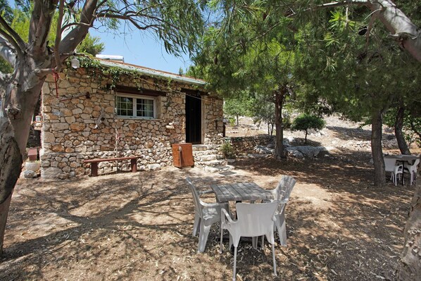 A stone building with a window, a bench, and a table with chairs.