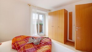 Een slaapkamer met een bed, een kledingkast en een raam met gordijnen.