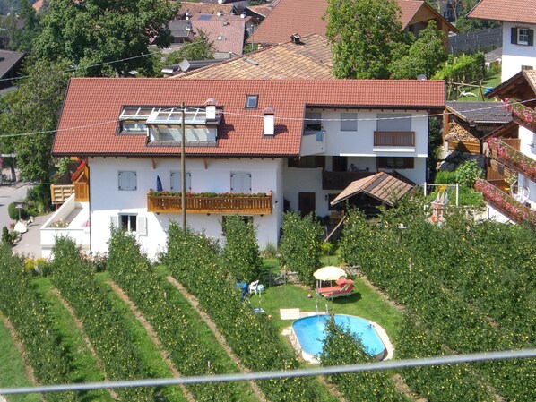 Un bâtiment à deux étages, doté d’un toit recouvert de tuiles rouges, d’une piscine et d’un jardin.