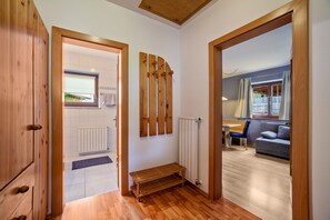 A hallway with wooden flooring, a bench, a radiator, and a window with a view.