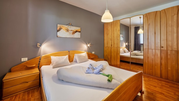 A bedroom with a wooden bed, a nightstand, a bedside table, a mirror, and a painting on the wall. - Apartment "Mosttragerhof 3" with Mountain View, Shared Pool & Wi-Fi (Scena)