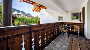 A balcony with wooden railings, a table with chairs, and a view of houses and mountains. - Apartment "Mosttragerhof 3" with Mountain View, Shared Pool & Wi-Fi (Scena)