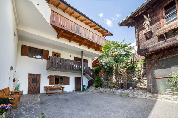 Un edificio de varios pisos con balcones, un muro de piedra y una valla de madera.