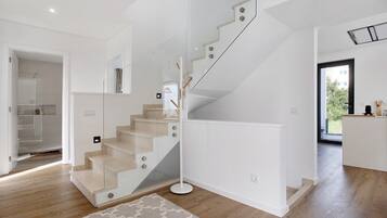 Ein modernes Interieur mit einer Treppe, einer Küchenzeile und Blick durch eine Glastür.