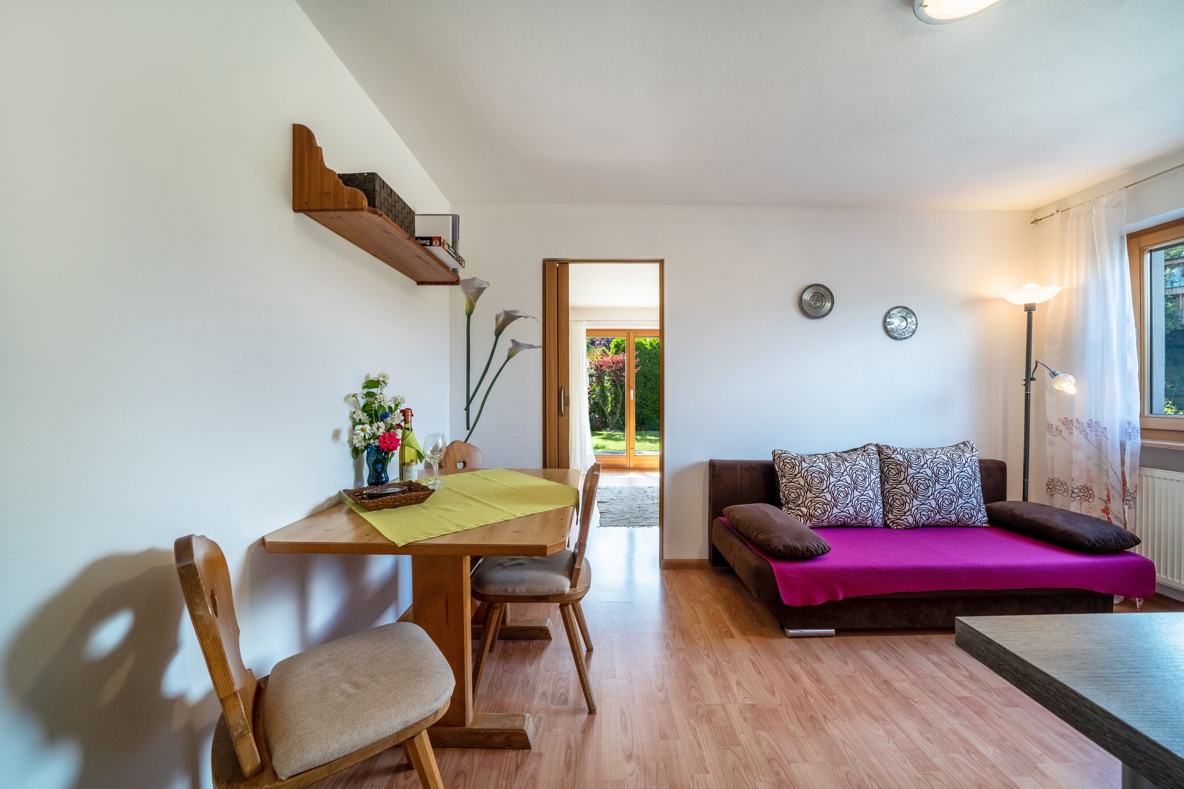 Una habitación con una mesa de madera para comer, sillas, un sofá y una lámpara.