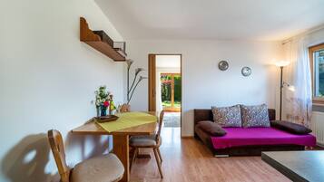 Una habitación con una mesa de madera para comer, sillas, un sofá y una lámpara.