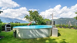 Una piscina con uno scivolo, circondata da un prato curato e vista sulle montagne.