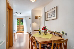 Un coin repas avec une table en bois, des chaises, un vase de fleurs et un tableau encadré au mur.