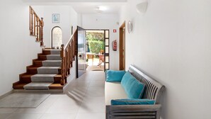 Eine Treppe führt zu einem Balkon, ein Sofa mit Kissen und ein Feuerlöscher an der Wand.