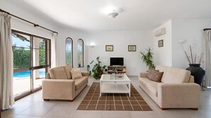 Ein Wohnzimmer mit zwei Sofas, einem Couchtisch, einem Fernseher und einem Bücherregal.