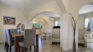 Ein geräumiger Wohnbereich mit Esstisch, Stühlen, Sofas und einem Fernseher.