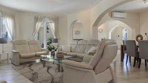 Ein geräumiges Wohnzimmer mit einer Sofagarnitur, einem Glastisch und einem Essbereich mit Stühlen.