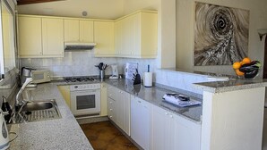 A kitchen with white cabinets, a stove, a microwave, and a sink. - Villa 'La Vista' with Sea View, Wi-Fi and Air Conditioning (Moraira)