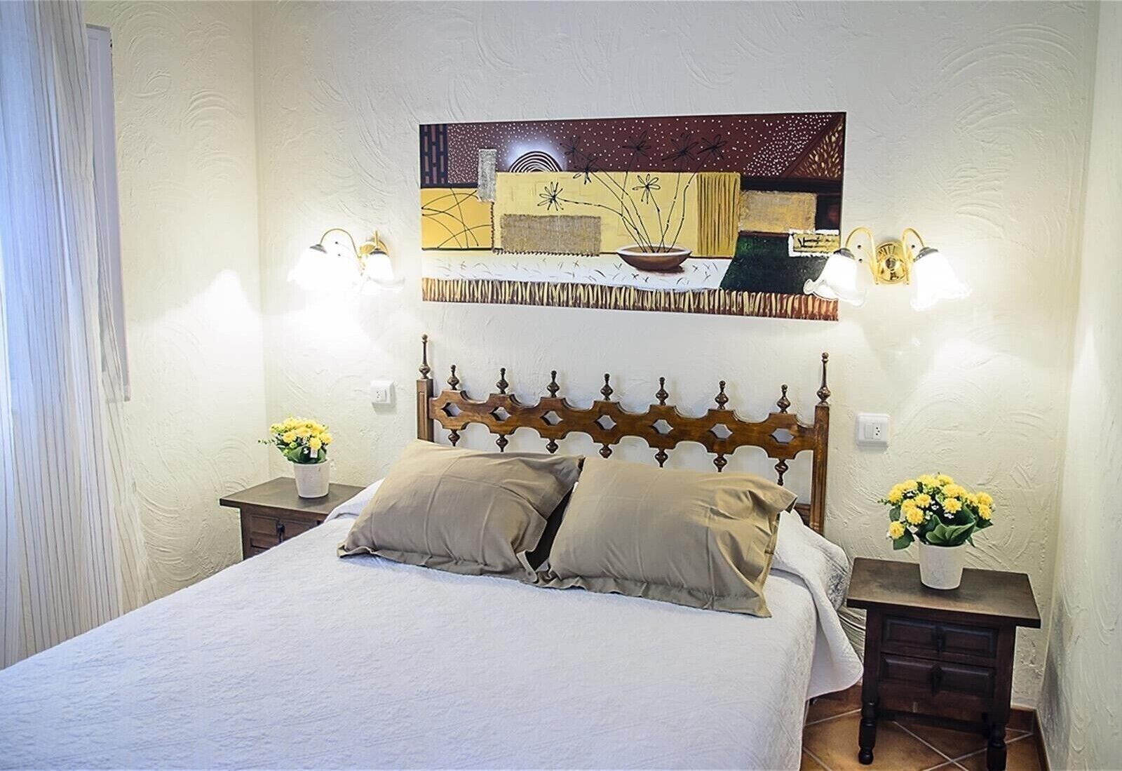 A bed with a wooden headboard, two bedside tables with lamps, and a wall-mounted shelf with decorative items.