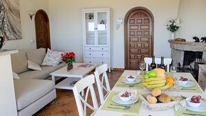 A dining area with a table set for four, surrounded by white chairs, a sofa, and a cabinet with glass doors. - Villa 'La Vista' with Sea View, Wi-Fi and Air Conditioning (Moraira)