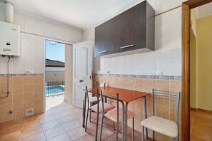 Eine Küche mit Esstisch, Stühlen, einem Durchlauferhitzer und Blick auf einen Swimmingpool.