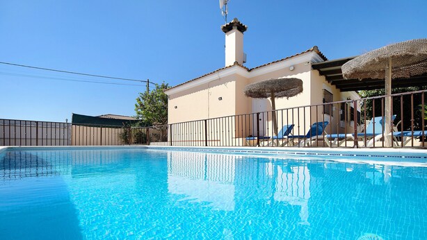Une piscine avec des chaises longues et un bâtiment doté d’une cheminée.