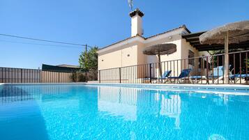 A swimming pool with lounge chairs and a building with a chimney.