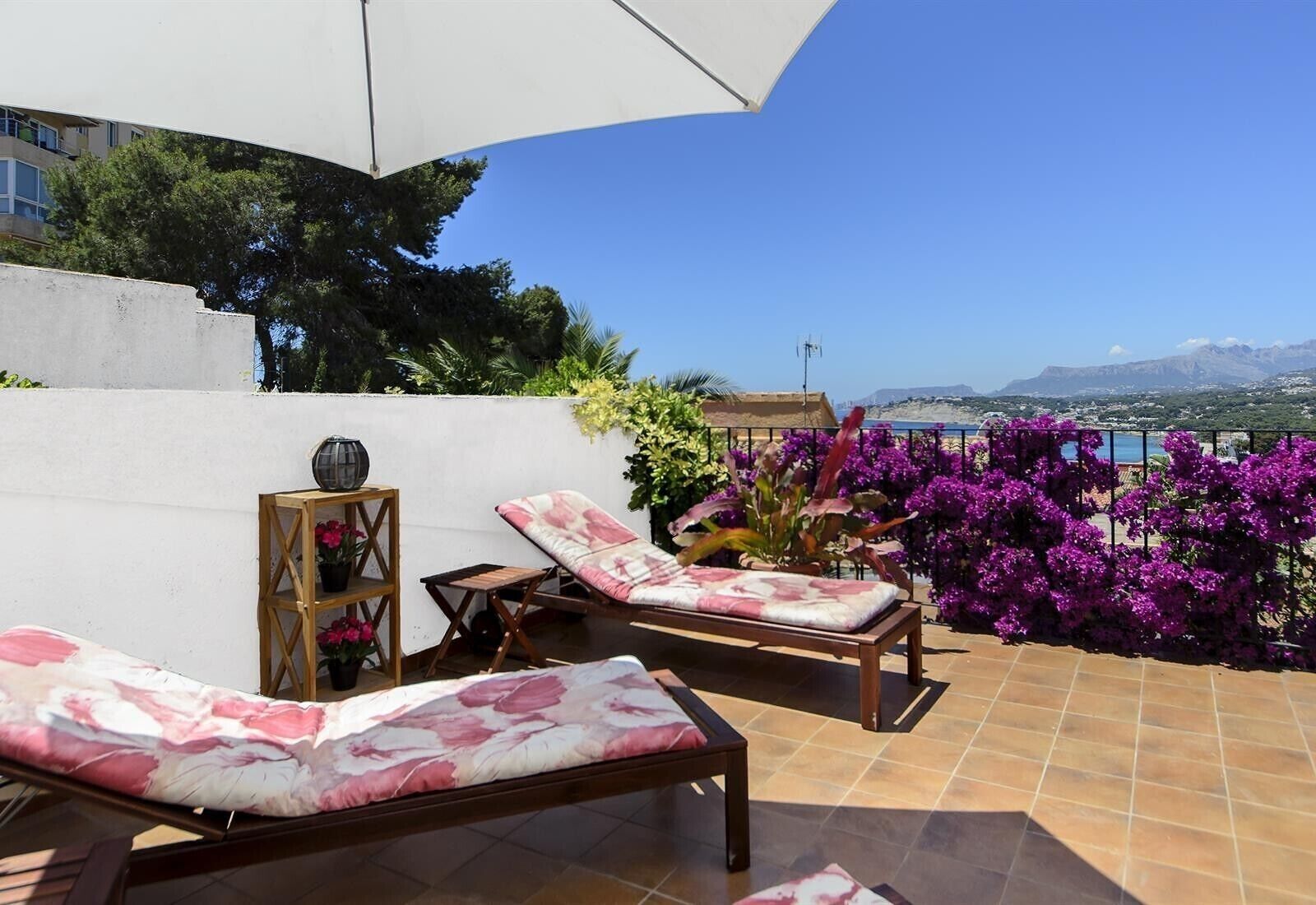 A terrace with two lounge chairs, a small table, and a potted plant.