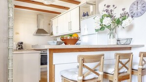 A kitchen with white cabinets, a wooden ceiling, a coffee maker, and a clock on the wall. - Holiday Home "Vista Bahia" with Sea Views, Private Pool and Wi-Fi (Moraira)