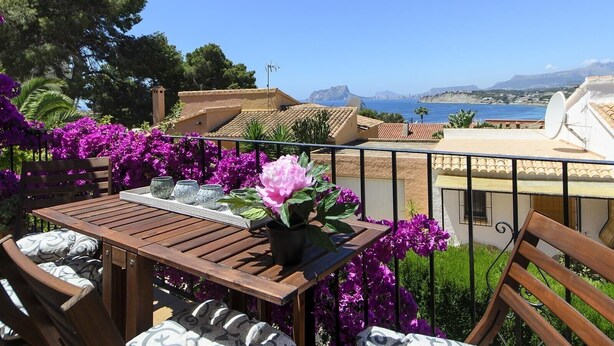 A balcony with a table, chairs, and purple flowers. - Holiday Home "Vista Bahia" with Sea Views, Private Pool and Wi-Fi (Moraira)