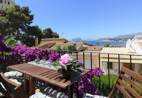 A balcony with a table, chairs, and purple flowers.. Holiday Home "Vista Bahia" with Sea Views, Private Pool and Wi-Fi