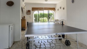 A ping pong table in a room with a view of greenery, a small refrigerator, and a window with blinds. - Holiday Home "Vista Bahia" with Sea Views, Private Pool and Wi-Fi (Moraira)