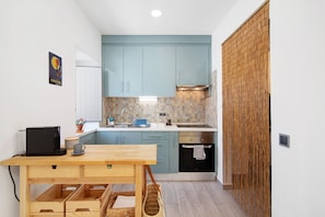 Una cocina compacta con armarios azul claro, una mesa de madera y una separador de bambú.