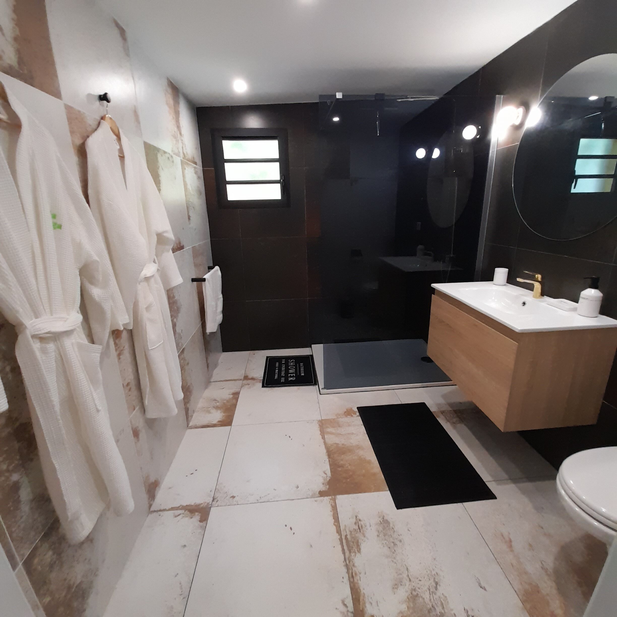 A modern bathroom with a large mirror, a sink, and a shower area.