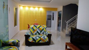 Una sala de estar con un sofá, un sillón negro y una escalera.