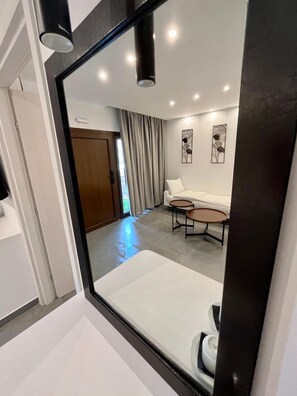 A modern interior with a white sofa, two small round tables, and a wooden door. - Skopelos Holidays Hotel (Skopelos)
