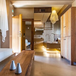A modern hotel lobby with a wooden reception desk, a seating area, and a view into a bedroom. - Skopelos Holidays Hotel (Skopelos)