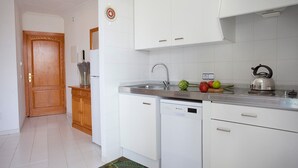 Una cocina moderna con armarios blancos, un lavamanos de acero inoxidable y un lavavajillas.