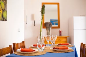 A dining table set with placemats, wine glasses, and a vase with a plant.