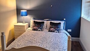 A bedroom with a bed, a nightstand, a lamp, and a chandelier. - 2-bed Apartment Sleeps 6 With Parking (Kildangan)