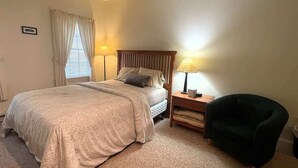 Een slaapkamer met een bed, nachtkastjes, een stoel en een lamp.