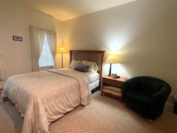 Une chambre à coucher avec un lit, des tables de chevet, une chaise et une lampe.