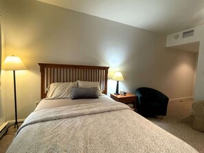 Une chambre à coucher avec un lit, deux lampes de chevet, une chaise et une petite table.