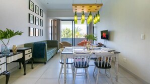 Ein modernes Wohnzimmer mit Essbereich, einem grünen Sofa, einem Fernseher und einem Balkon mit Blick.
