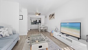 A modern living room with a foosball table, a TV, and a kitchen in the background.