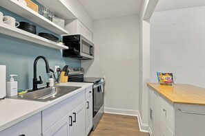 A compact kitchen with a sink, stove, microwave, and cabinets.