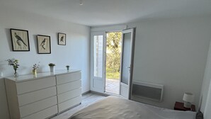 Un dormitorio con cama, cómoda y puerta que da a un balcón.