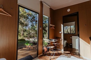 Ein modernes Interieur mit Holzboden, einer Essecke mit Tisch und Stühlen sowie einer Küchenzeile mit Kühlschrank.