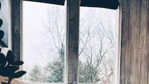 A bedroom with a large window, wooden walls, and a bed with white bedding. - The 212 Escape (Woodstock)