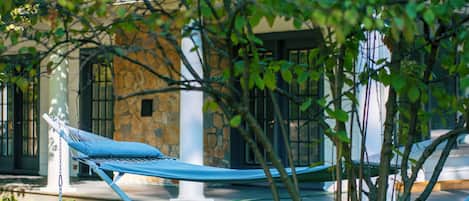 A hammock in a garden area with a stone building in the background.